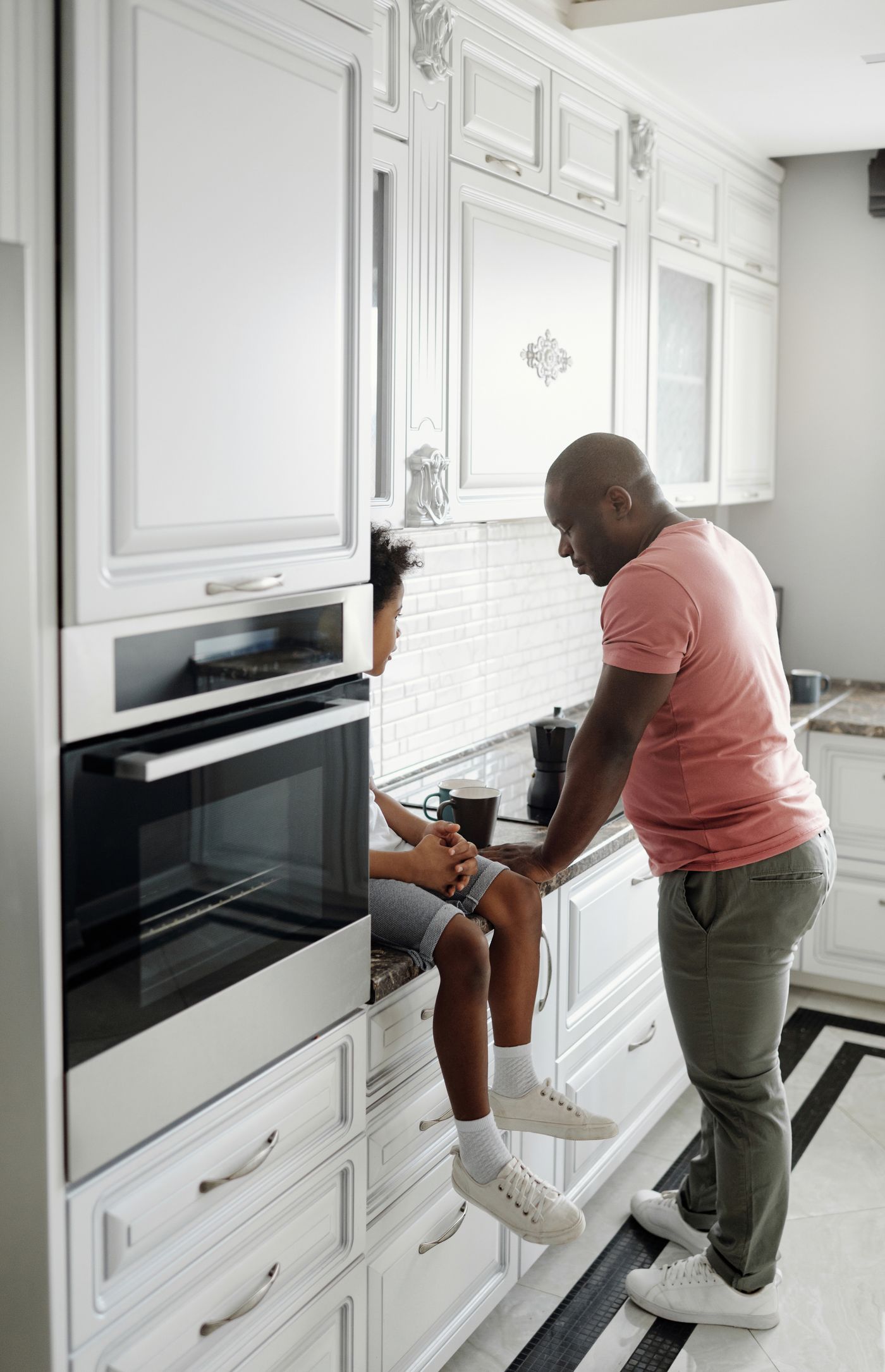 African American father and son talking together at the kitchen counter of their home