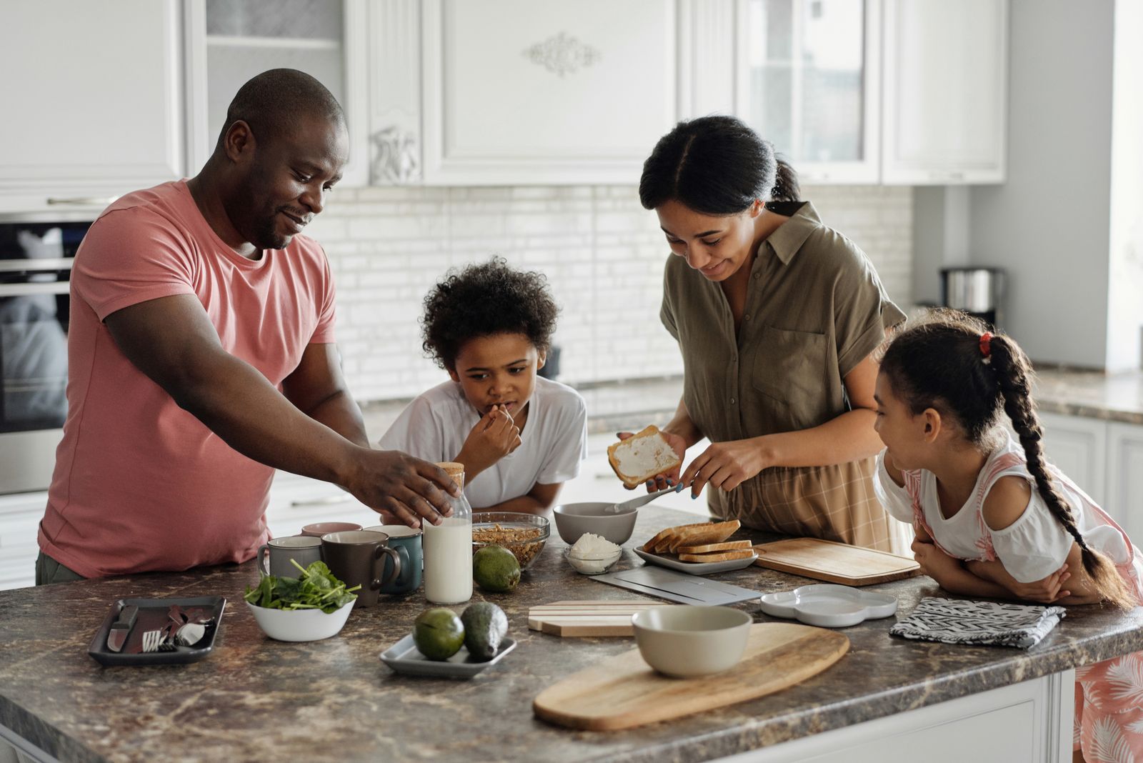 African American parents and their children preparing breakfast together in their kitchen
