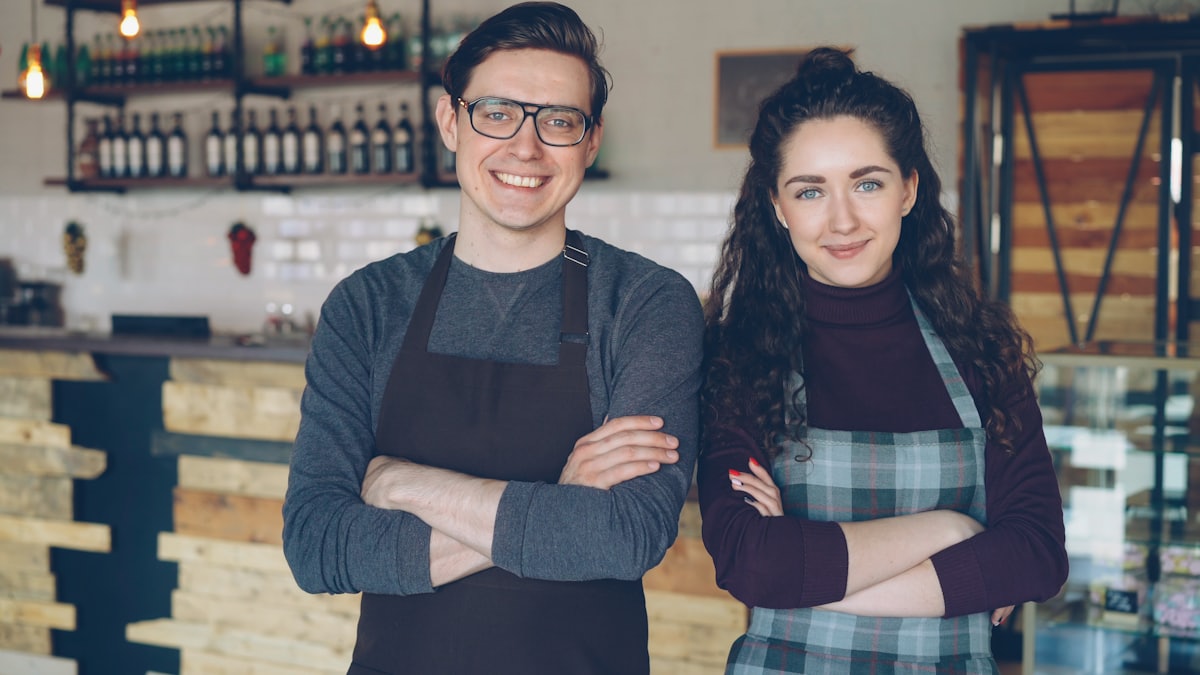 Two small business owners smiling together inside their cafe